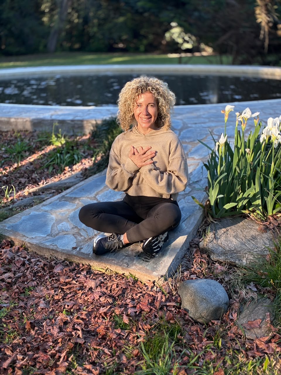 Sherine seated outdoors in a garden with her hands resting over her heart